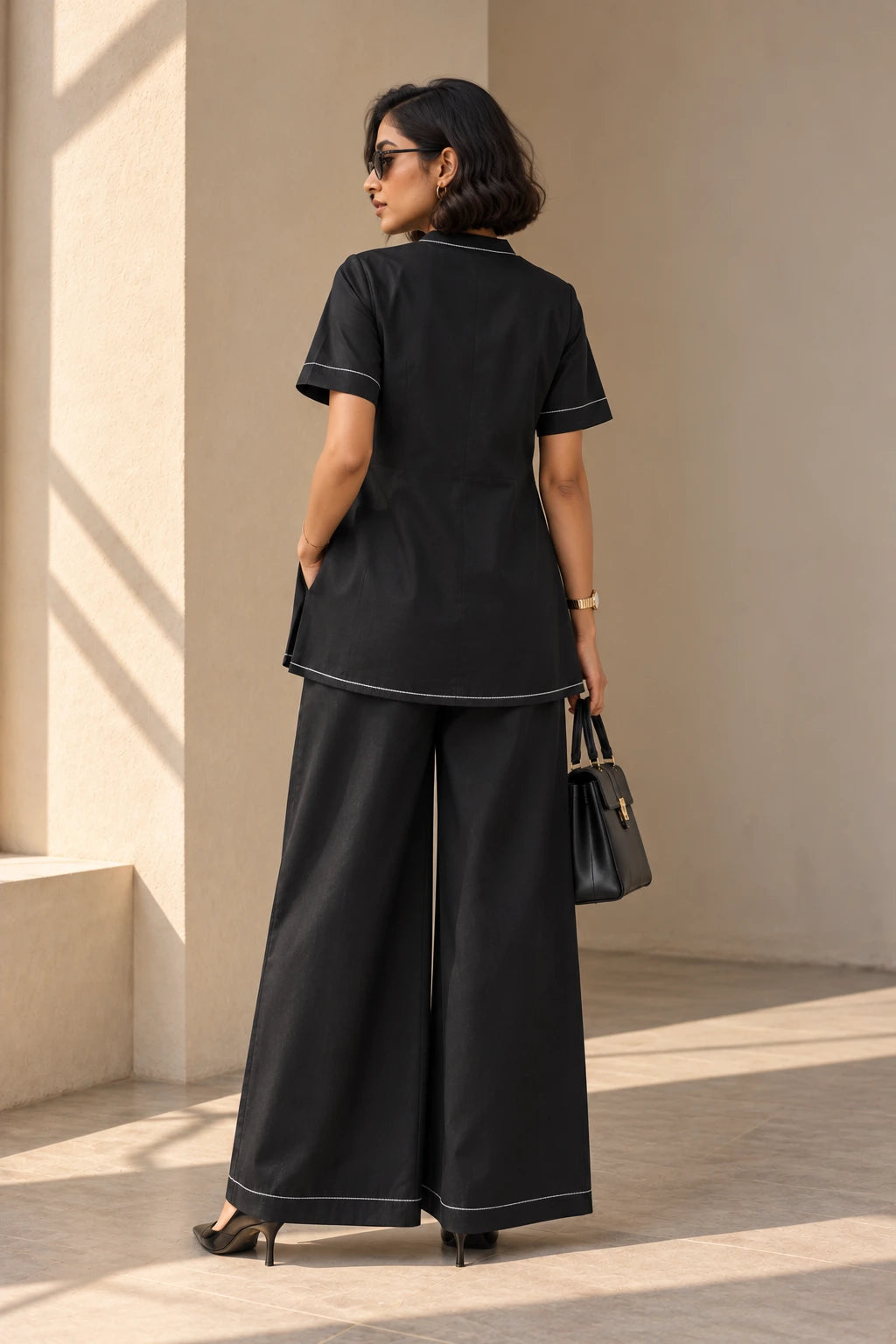 Back view of black contrast stitch kurta set showing short sleeves, stitched hems and full-length wide-leg palazzos