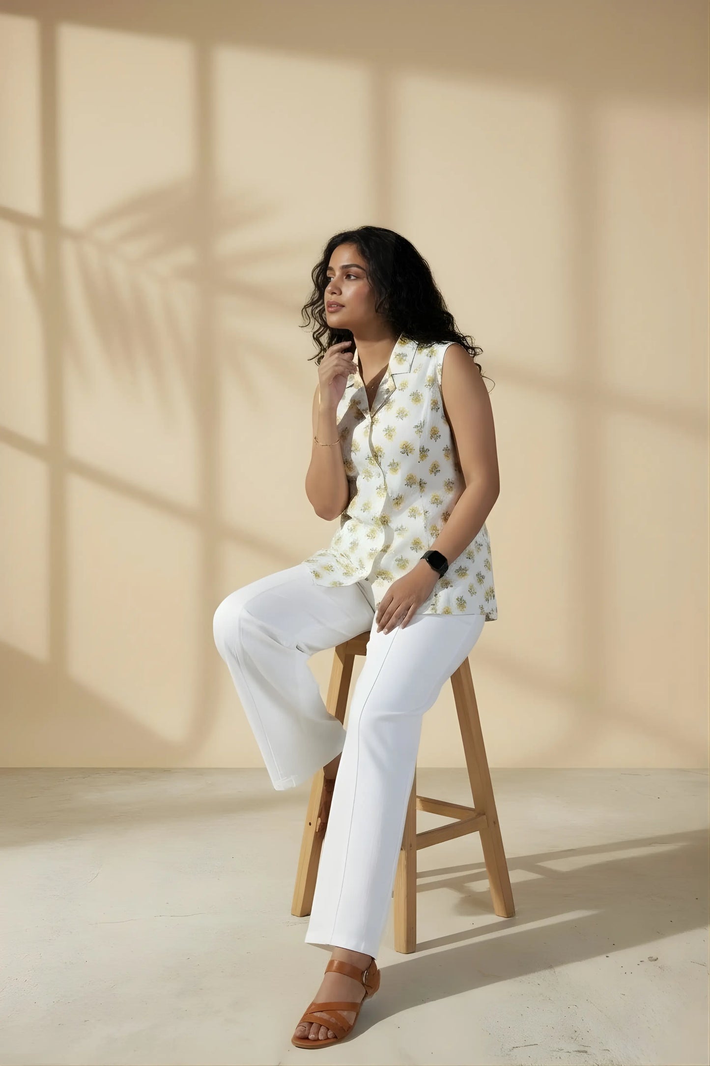 Model sitting on a chair wearing white floral vest top