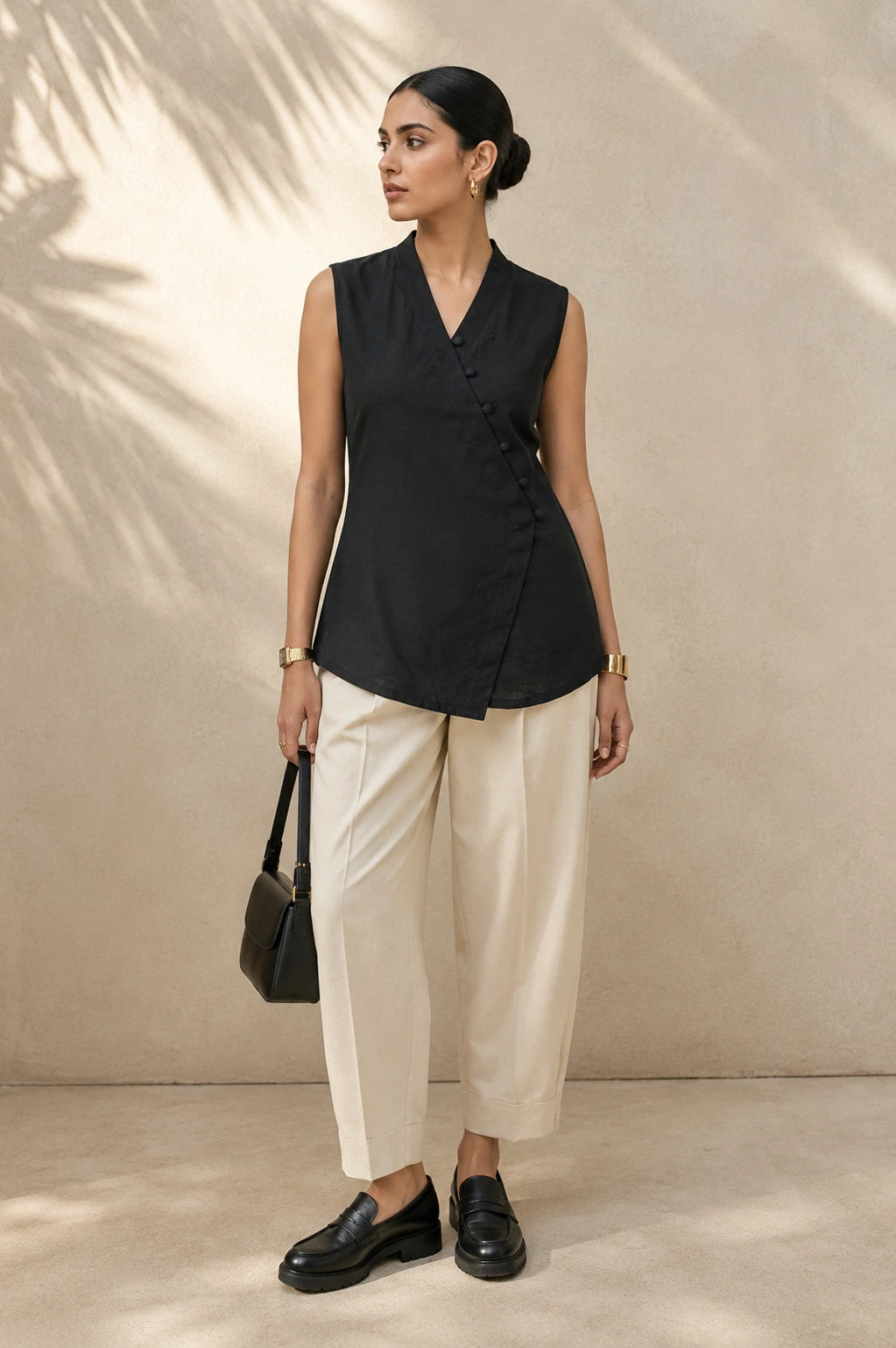 Black loop button wrap kurta, full front view, asymmetric wrap and diagonal loop button placket, styled with cream wide-leg trousers