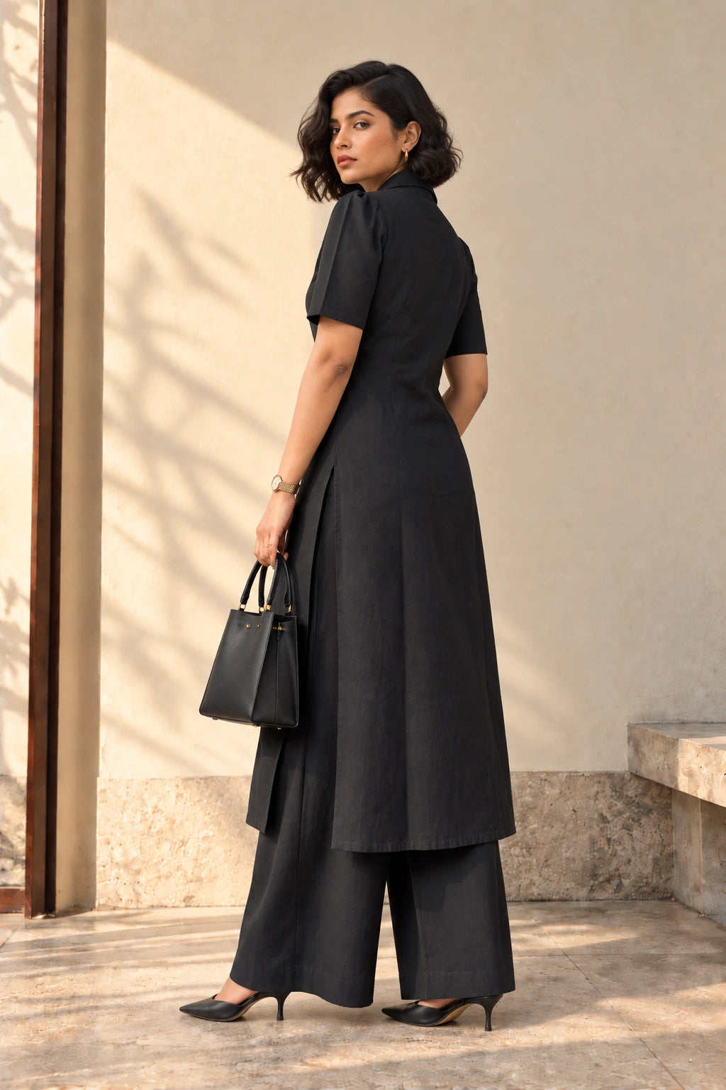 Side view of black double-breasted kurta set showing side slit, longline length and wide-leg palazzos
