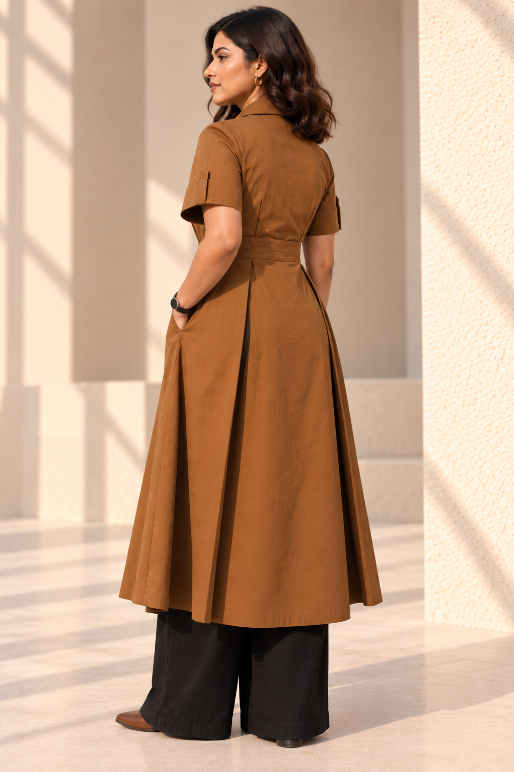 Side view of chestnut brown pleated wrap kurta showing side seam pocket, box pleats and longline length