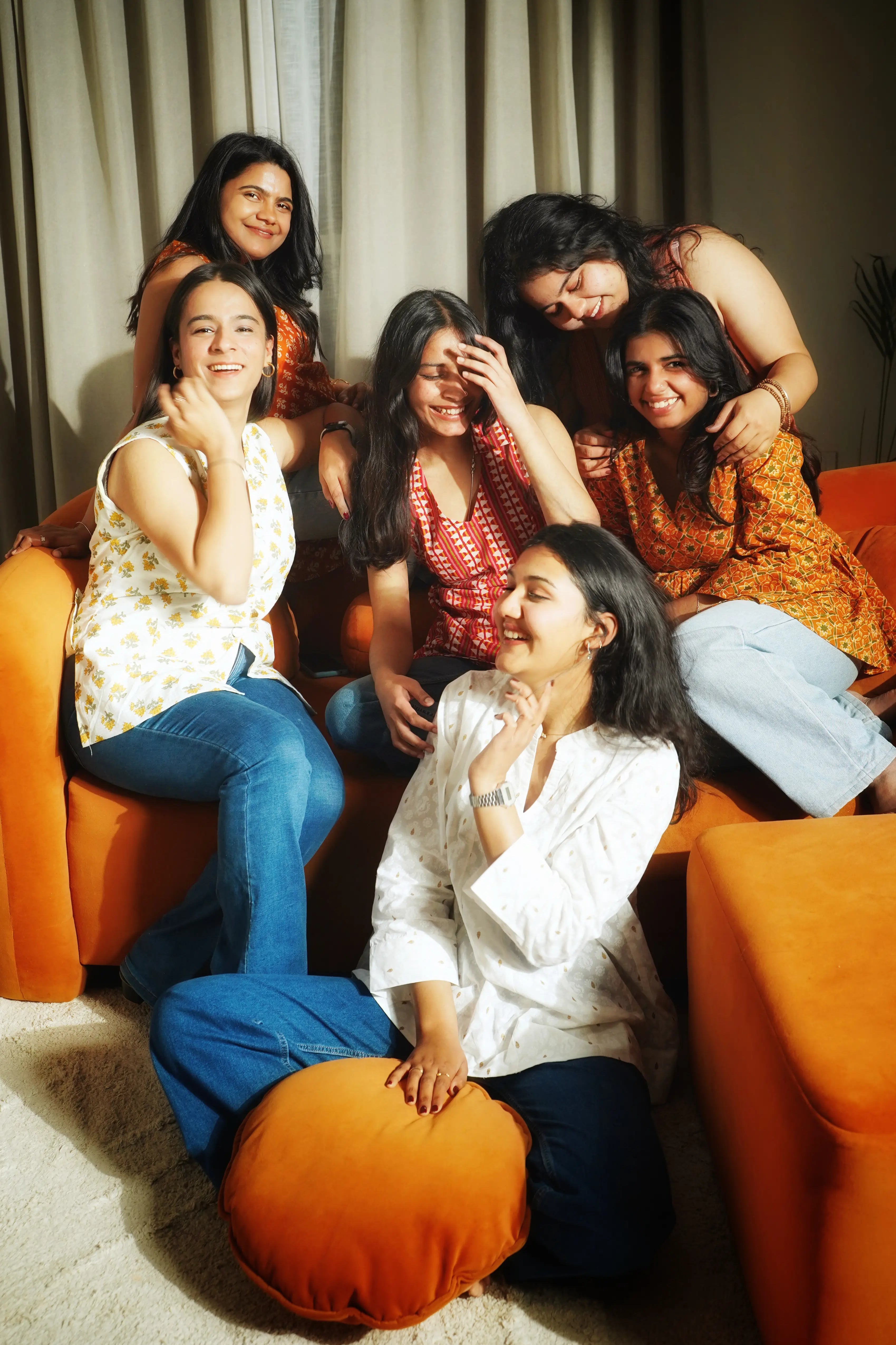 Friends playing a board game on a couch in versatile Swayra Indian wear, showcasing community and social transition.