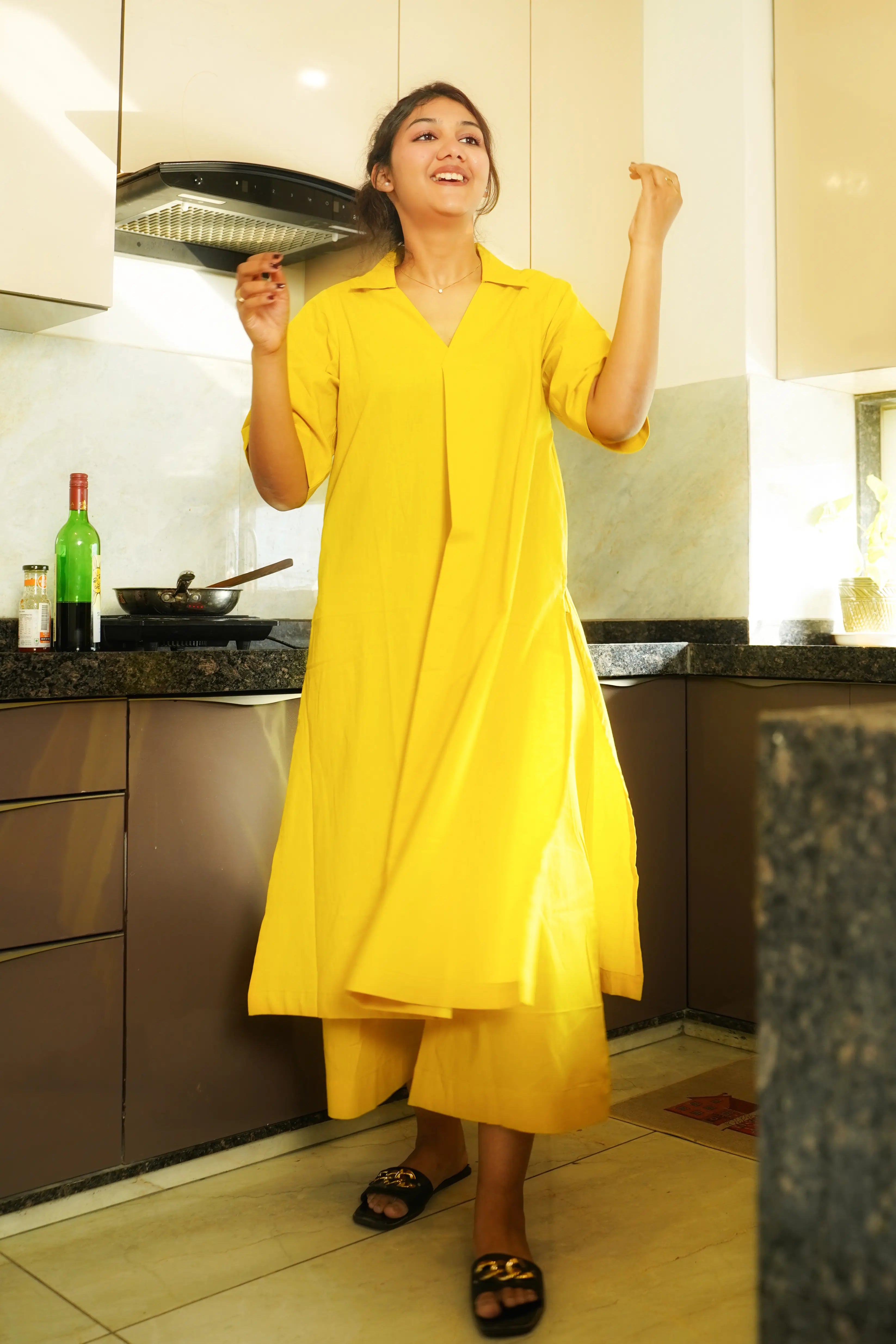 Woman wearing a Swayra yellow cotton kurta set in a modern kitchen, representing breathable Indian workwear for long workdays.