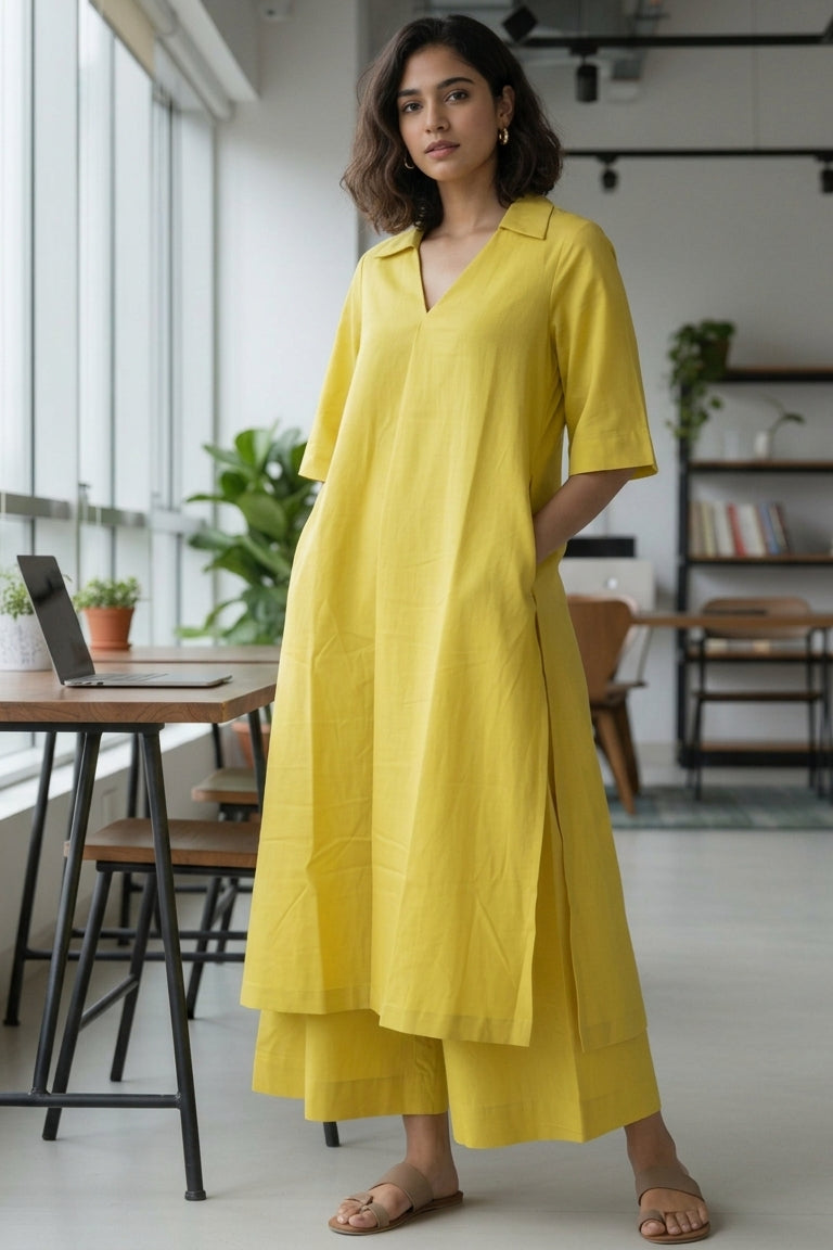 Woman in a yellow dress standing in a modern indoor setting with large windows and tables.
